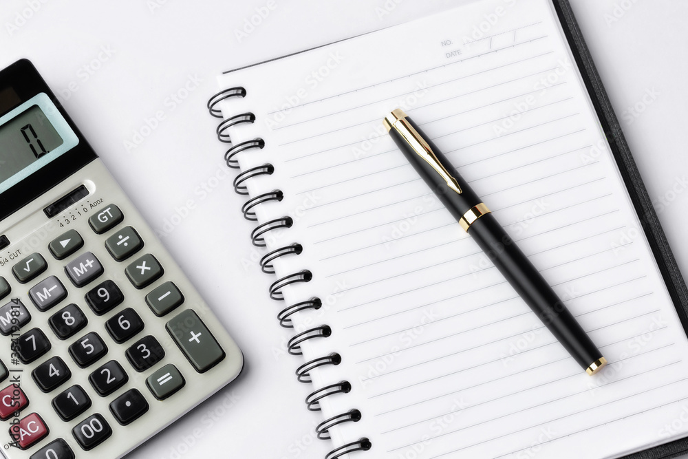 Pen, calculator on notebook close up on white background Pen, calculator on notebook close up on white background