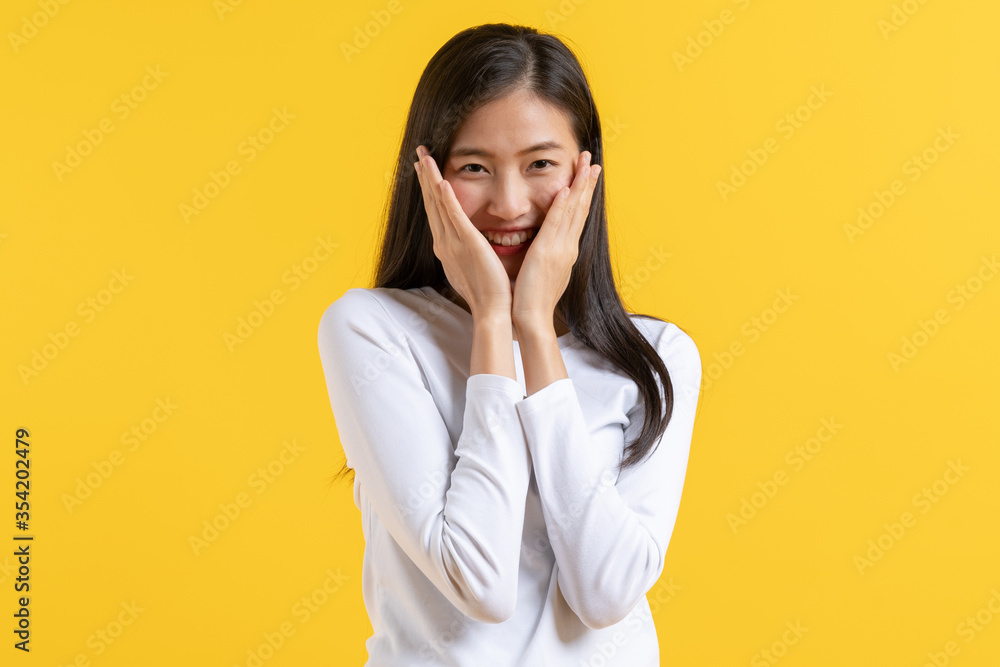 Asian teenager white shirt shy expression face on yellow background Asian teenager white shirt shy expression face on yellow background