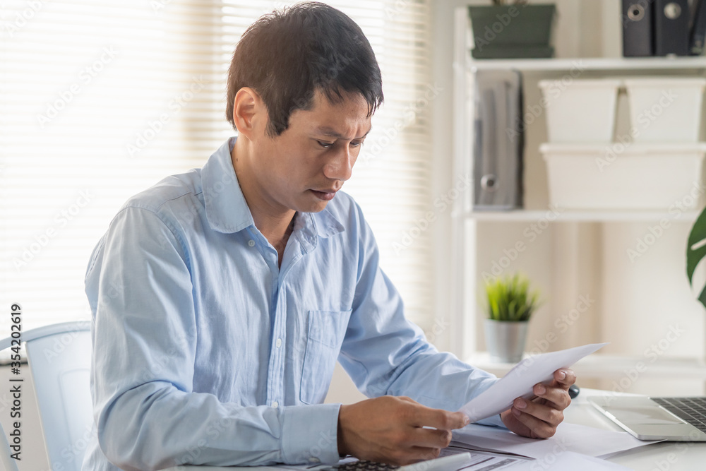 Stress Asian man looking at household invoice and credit card bills. Stress Asian man looking at household invoice and credit card bills.