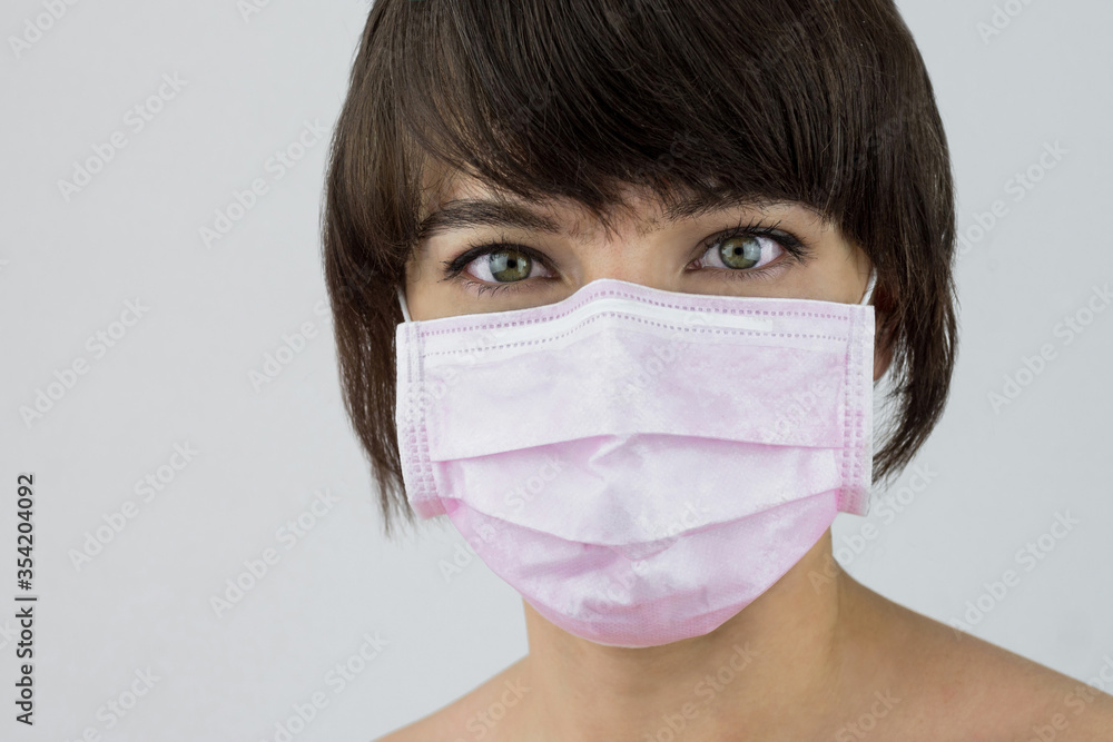 Woman portrait with green eyes and medical pink mask Woman portrait with green eyes and medical pink mask