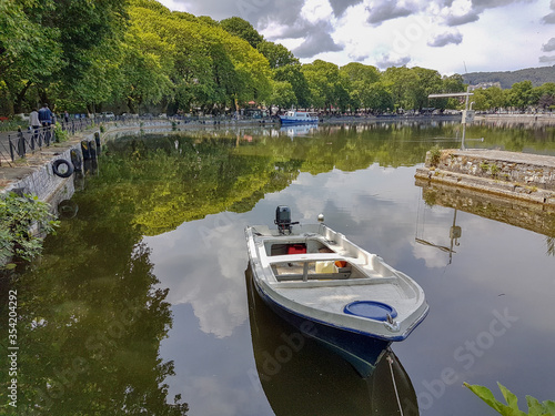 Ioannina city lake Pamvotis in spring season boat reflection of the clouds in the water green trees in greece photo