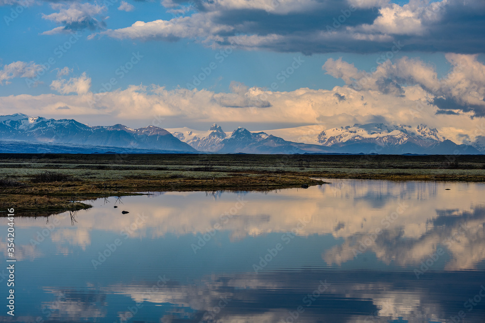 Snow covered mountains reflected in a shallow lake in Iceland