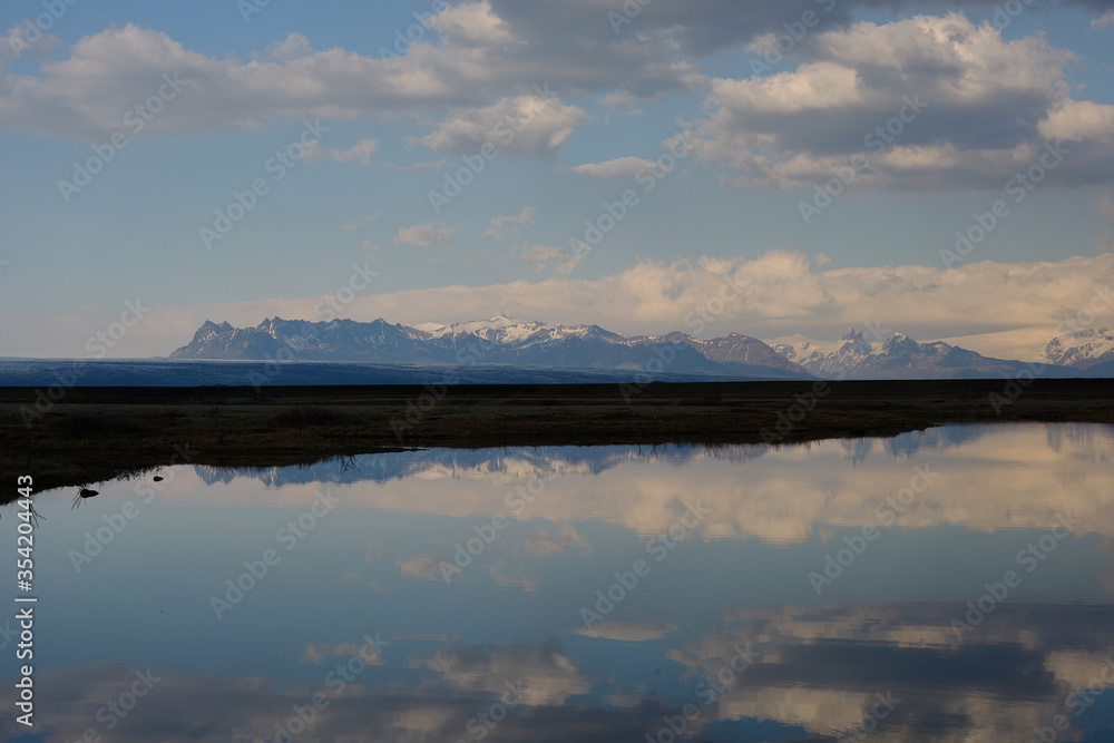 Snow covered mountains reflected in a shallow lake in Iceland