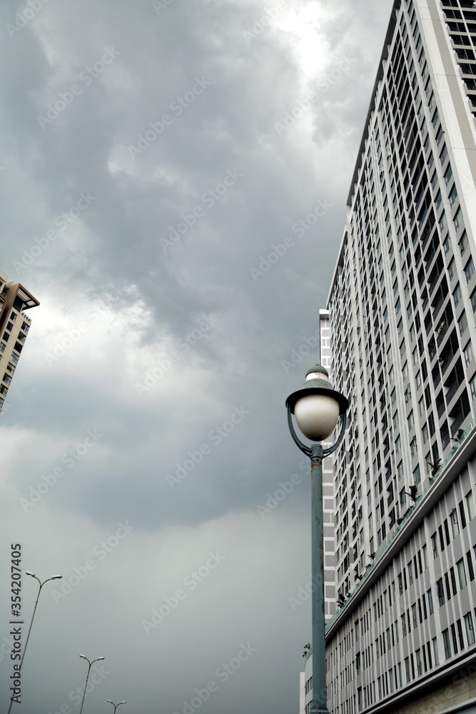 Obraz premium Tall gray buildings and lanterns in a city business district. Dull depressing city view on a cloudy day. Architectural background with copy space