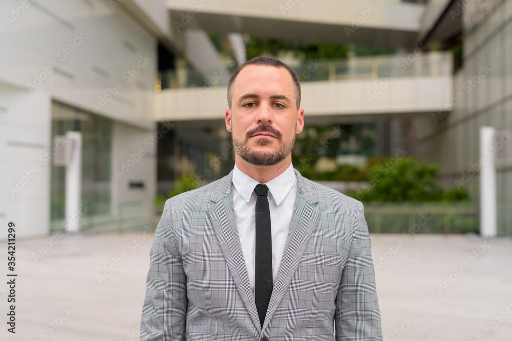 Handsome Hispanic bald bearded businessman in the city outdoors Handsome Hispanic bald bearded businessman in the city outdoors