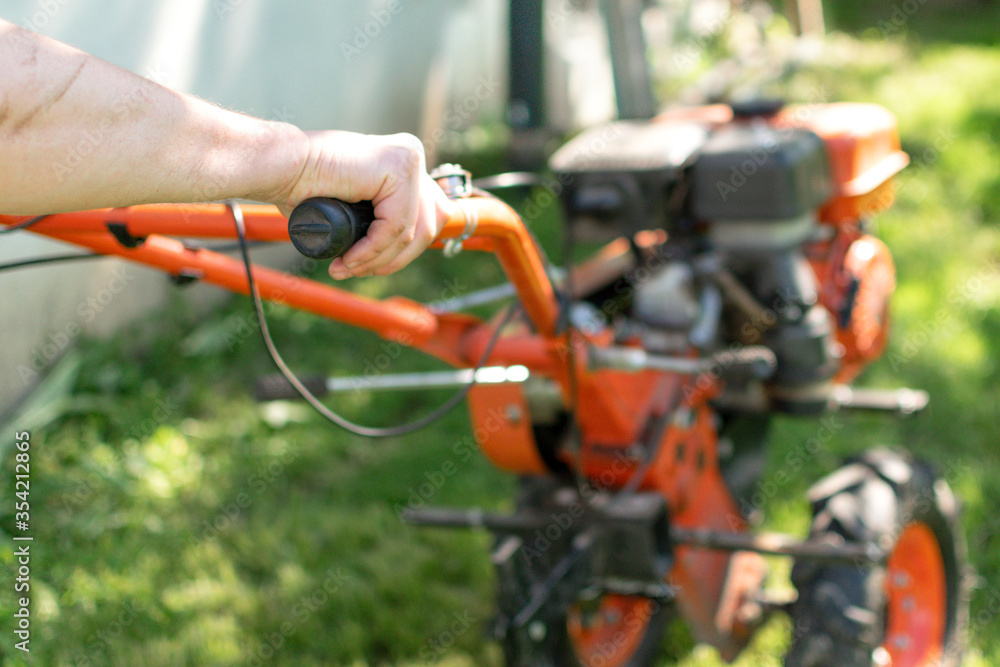 Man Farmer plows the land with a cultivator. Agricultural machinery: cultivator for tillage in the garden,motor cultivator Man Farmer plows the land with a cultivator. Agricultural machinery: cultivator for tillage in the garden,motor cultivator