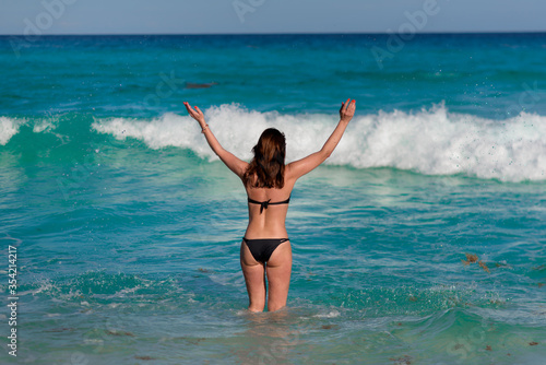 A woman on the beach looks at the horizon and walks along the beach.