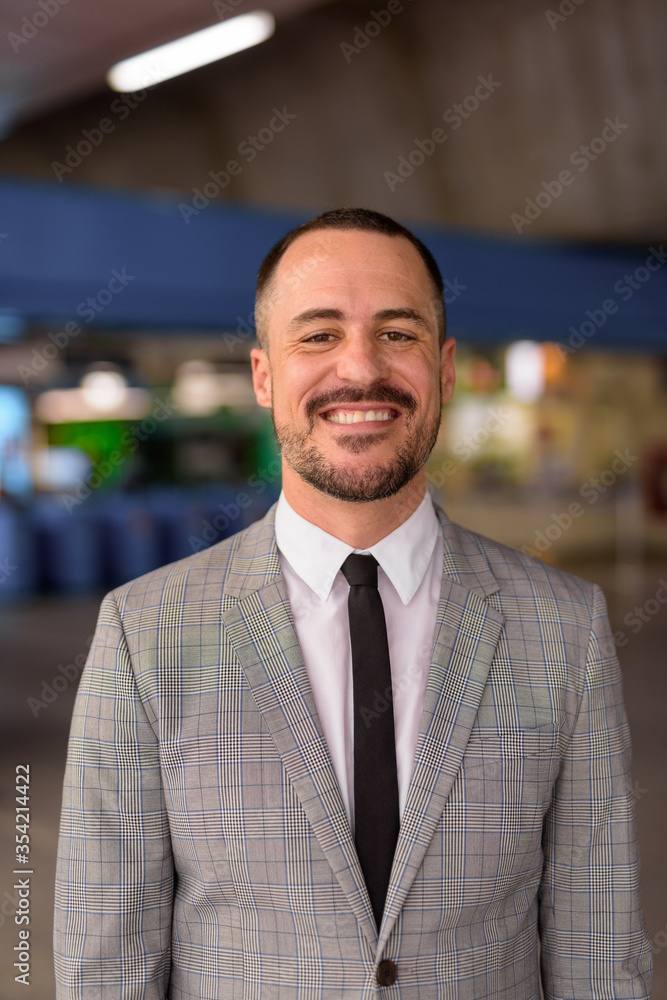 Happy Hispanic bald bearded businessman smiling at the sky train station