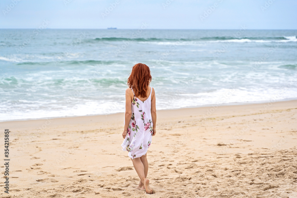 Relaxed woman enjoying ocean, freedom and life at beach. Young lady feeling free, relaxed and happy. Concept of freedom, happiness, enjoyment and well being.