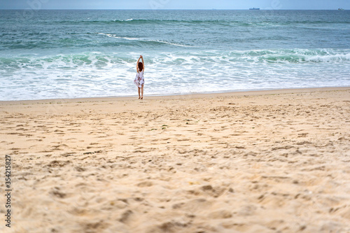 Relaxed woman enjoying ocean, freedom and life at beach. Young lady feeling free, relaxed and happy. Concept of freedom, happiness, enjoyment and well being.