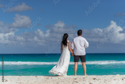 A man and a woman walk on the seashore and look at the horizon.