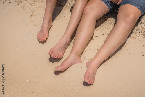 Feet of man and woman on the yellow sand.