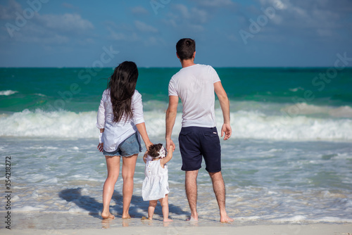 Parents with a small child walk on the beach and admire the horizon.