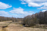 Early spring in a landscape with a small river, a birch forest and a field.