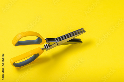 Scissors with five blades on a yellow background. photo