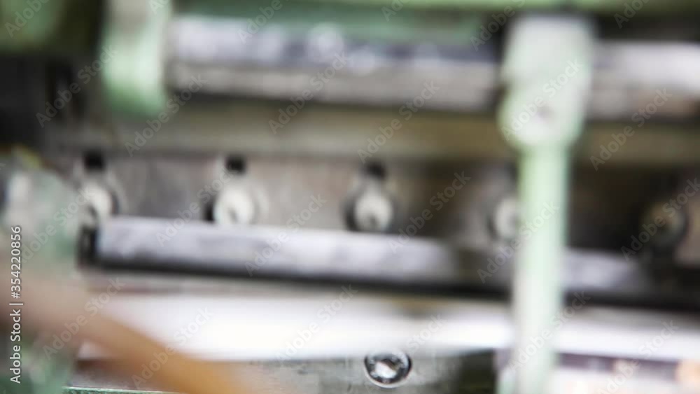 An industrial knife cuts the edges of books in a printing press An industrial knife cuts the edges of books in a printing press