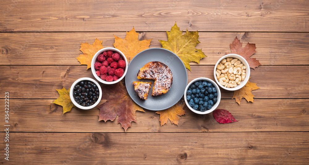 Seasonal autumn background. Frame of maple leaves and a cake over wooden background. Seasonal autumn background. Frame of maple leaves and a cake over wooden background.