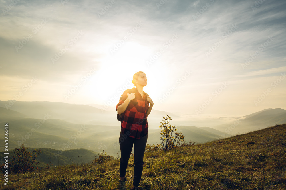 Young Woman Traveler In Red Plaid Shirt With Backpack Climbs Uphill At Sunrise. Scout Travel Adventure Concept