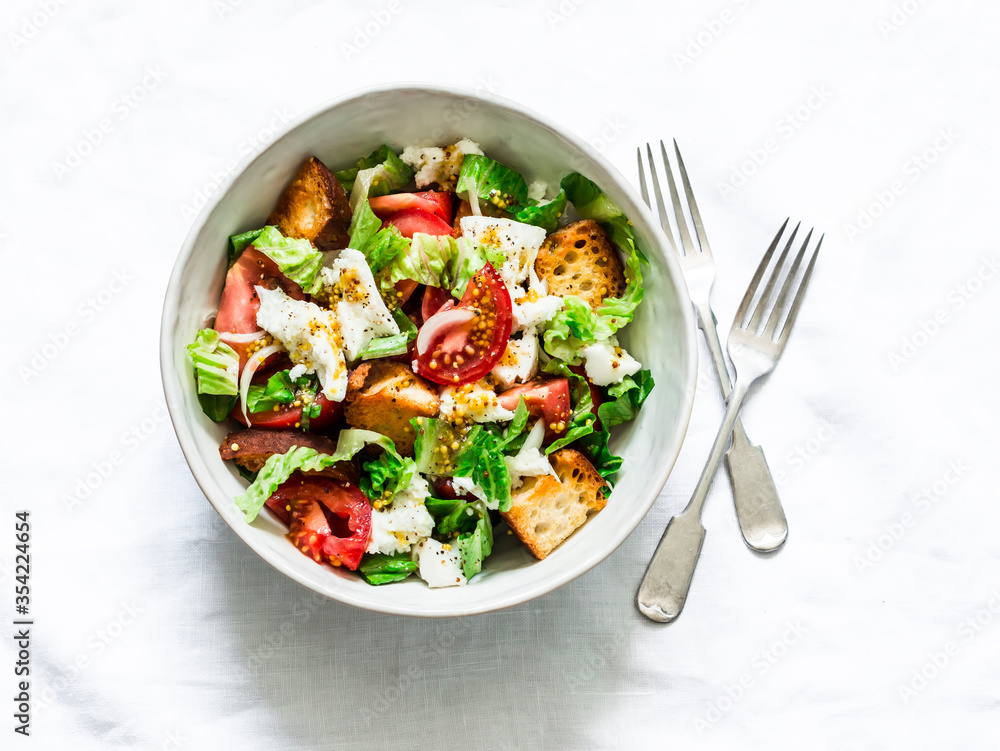 Rustic italian salad with fresh tomatoes, crispy ciabatta, mozzarella cheese, green salad with olive oil, mustard, lemon dressing on a light background, top view Rustic italian salad with fresh tomatoes, crispy ciabatta, mozzarella cheese, green salad with olive oil, mustard, lemon dressing on a light background, top view