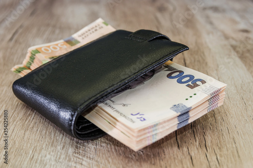 500 hryvnia in a black men's wallet on a wooden background. Close-up. A lot of hryvnia.