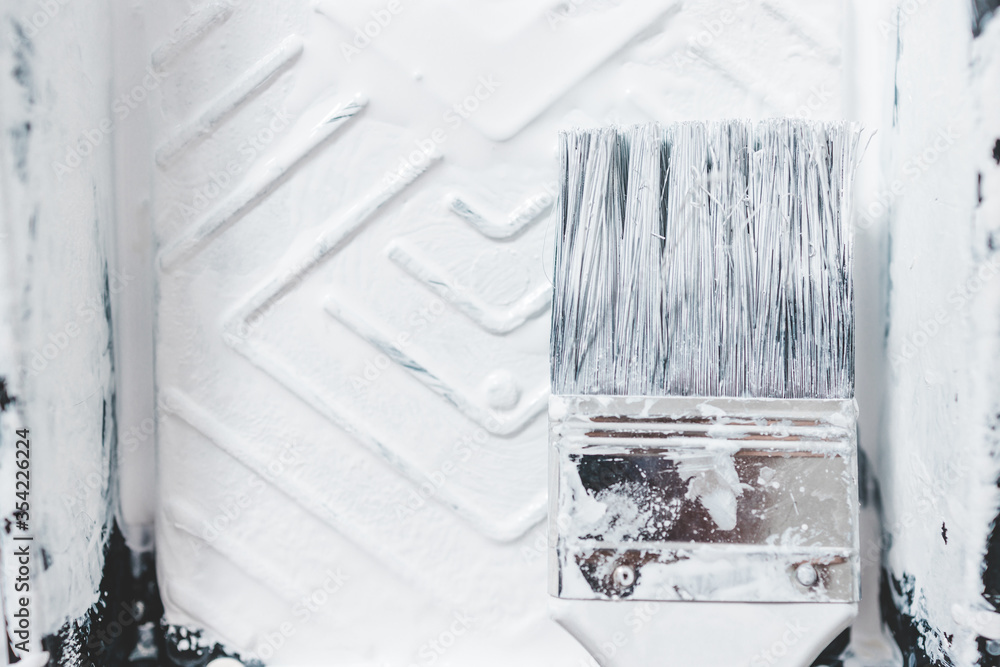 DIY and home improvement, close-up of paint tray with white glossy paint and paint brush on it DIY and home improvement, close-up of paint tray with white glossy paint and paint brush on it