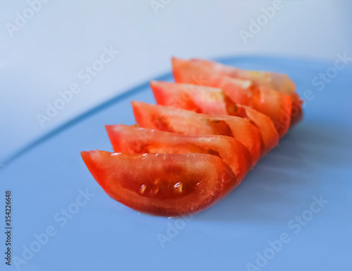 Tomato slices on cutting board. Blue background. Tomato slice concept.Sale,cooking photo