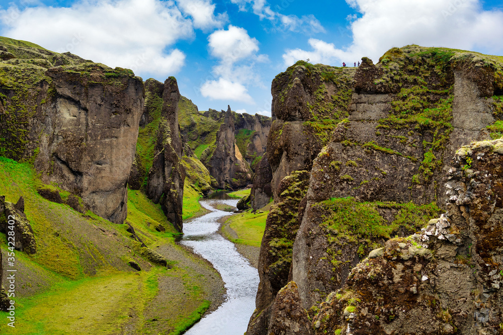 Amazing view at Fjadrargljufur Canyon is a deep canyon in the south-eastern part of Iceland. The Fjaðrá River flows through steep walls and meandering water, in summer with green grass and blue skies.