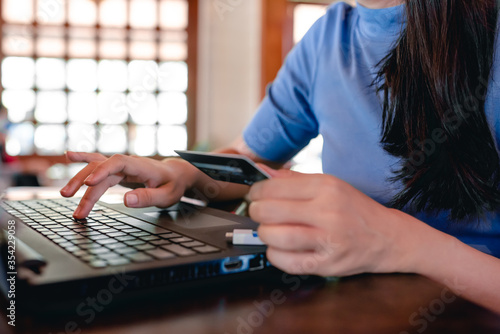 Beautiful Asian women working freelance at home. She enjoys shopping online with a credit card. Use a credit card to buy online via computer. The concept of happy online shopping at home