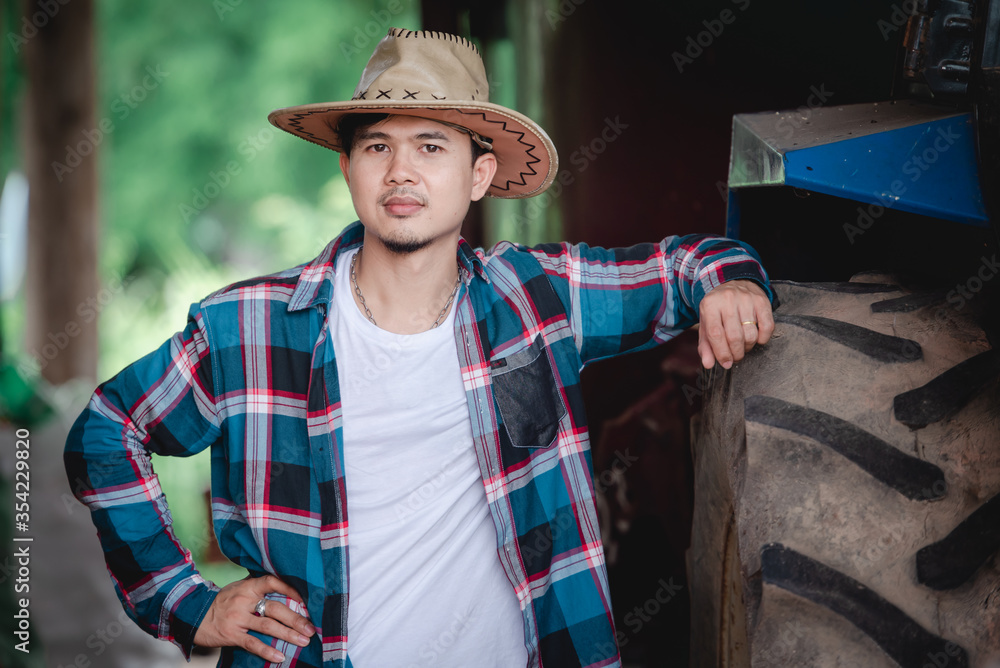 Pictures of handsome Asian men wearing smiling shirts beside tractors for farmers and farmers. Concept: Biological ecology, beautiful and healthy environment for farmers.