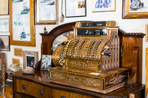 A picture of a golden vintage shop cash money register on a beautiful wooden cupboard