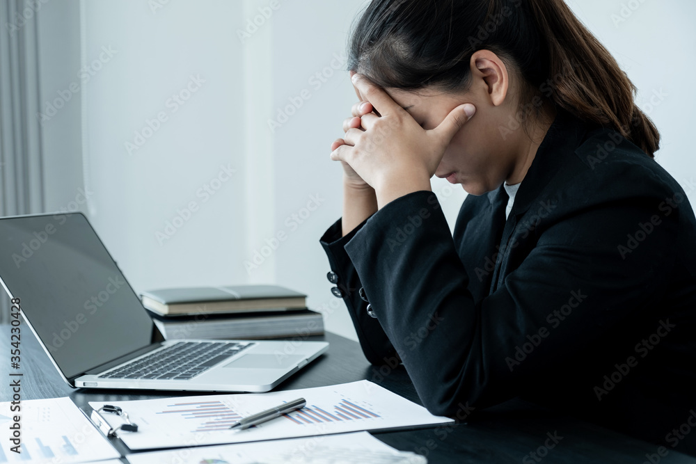A tired business woman with a stressful headache from work sitting at an office desk A tired business woman with a stressful headache from work sitting at an office desk