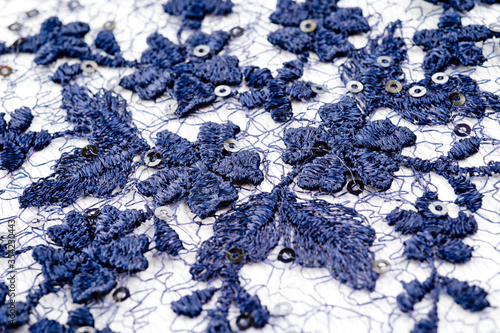 A blue guipure with volumetric embroidery of flowers and sequins, photographed in close-up.