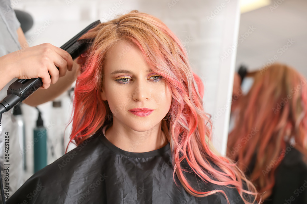Naklejka premium Female hairdresser doing hair of beautiful young woman in salon