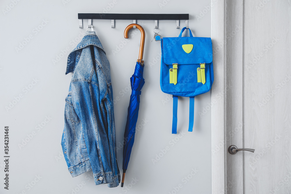Umbrella with clothes and school backpack hanging on wall in hall - obrazy, fototapety, plakaty 