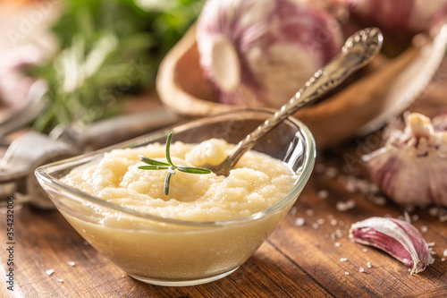 Fototapeta Garlic paste in a glass bowl with peeled garlic, salt, crusher and garlic heads