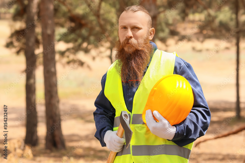 Handsome lumberjack with axe in forest Handsome lumberjack with axe in forest