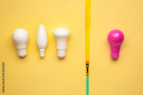 Pink light bulb among white ones on color background. Concept of uniqueness