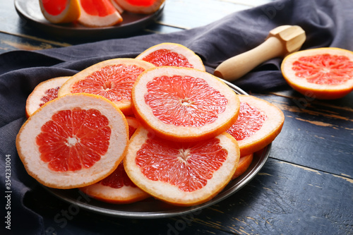 Plate with fresh cut grapefruit on dark wooden background