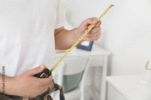 Male carpenter with tape measure in room  closeup