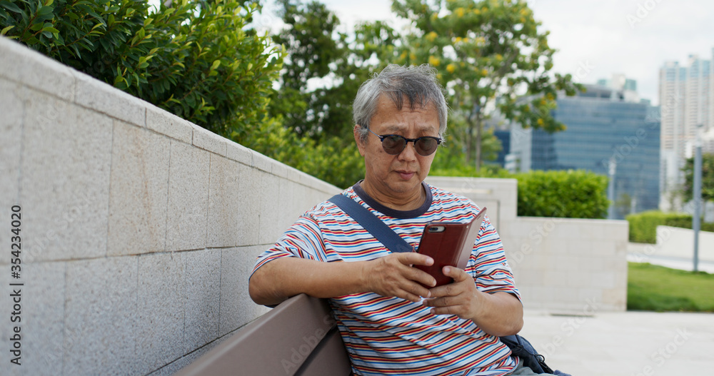 Obraz premium Asian old man use of mobile phone in city