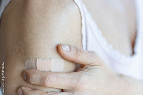 Woman using adhesive bandage plaster on her arm after injection vaccine.