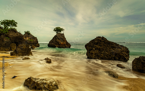 Beautiful seascape. Beach during daylight. Sandy beach with rocks. Waves captured with slow shutter speed. Soft focus. Bingin beach, Bali, Indonesia