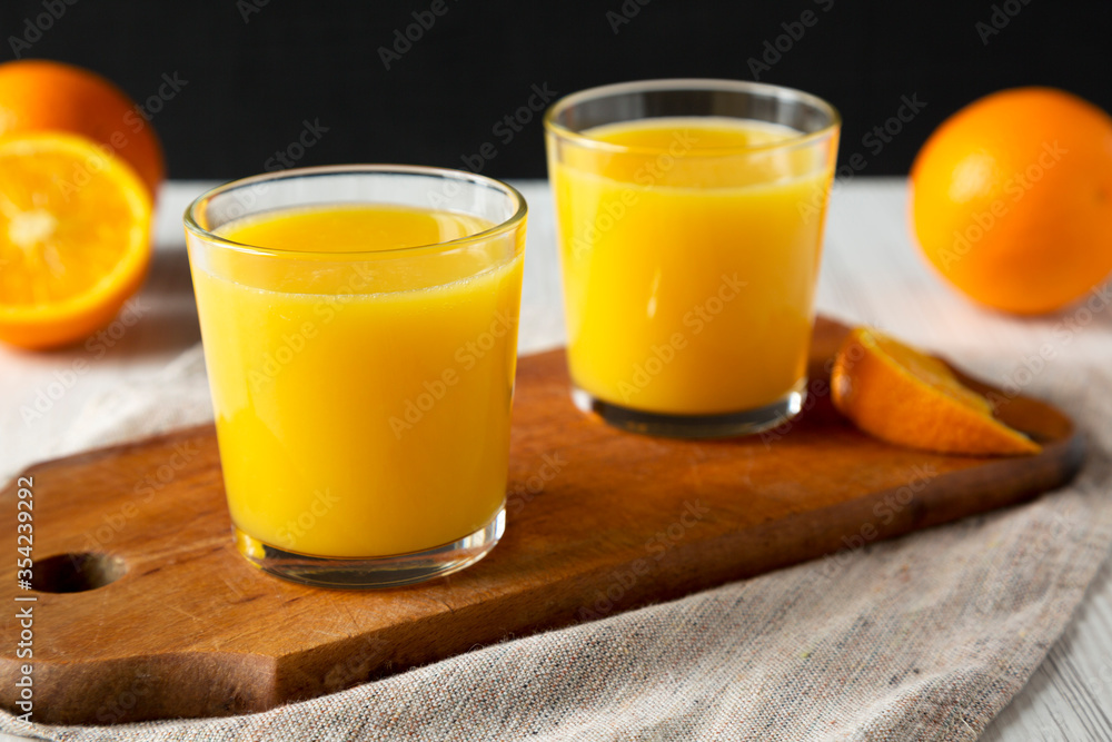 Healthy Orange Juice on a rustic board on a white wooden background, side view. Close-up. Healthy Orange Juice on a rustic board on a white wooden background, side view. Close-up.