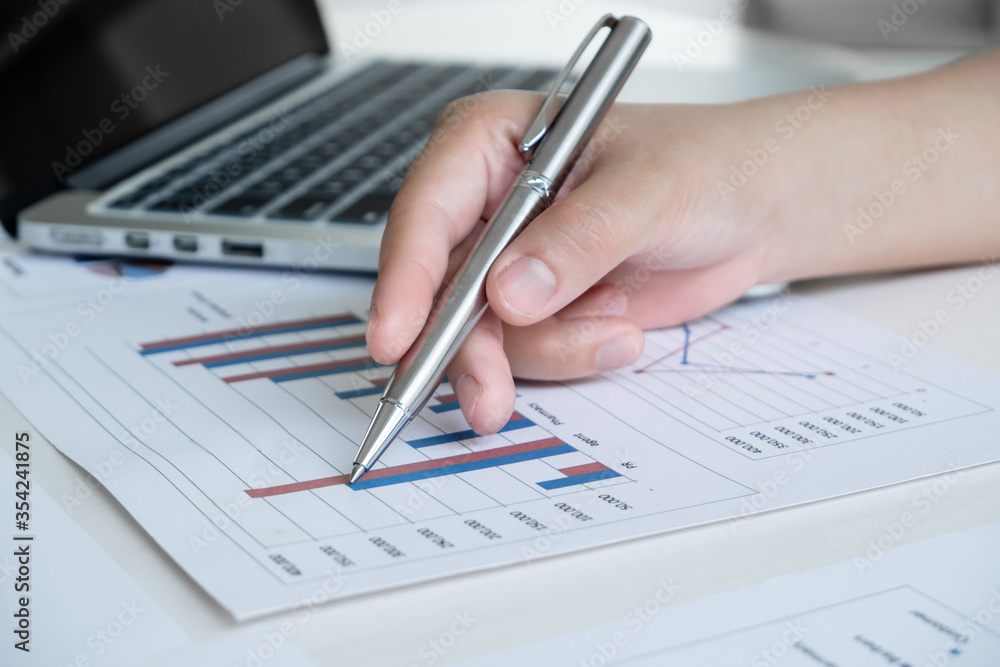 Office girl is sitting at a desk and calculating financial graph that show results In the office Office girl is sitting at a desk and calculating financial graph that show results In the office