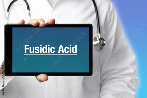 Fusidic Acid. Doctor in smock holds up a tablet computer. The term Fusidic Acid is in the display. Concept of disease, health, medicine photo
