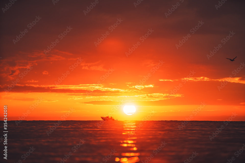 Silhouette of two people in a local small fishing boat moving with sunrise in the background