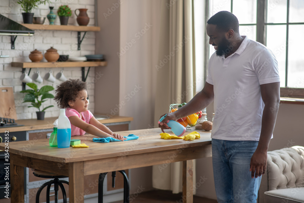 African american tall bearded man spraying disinfector on the table surface African american tall bearded man spraying disinfector on the table surface