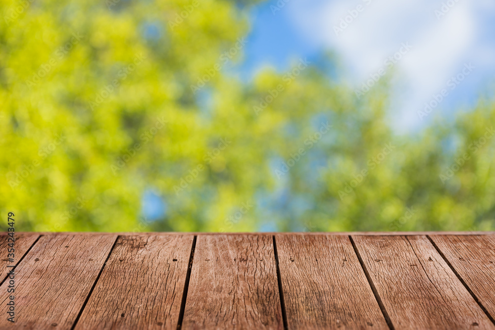 blur green tree background with wooden table foreground for advertising natural products overlay template. blur green tree background with wooden table foreground for advertising natural products overlay template.