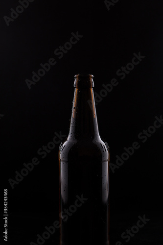 Bottle of beer with drops of water close-up on a black isolated background.