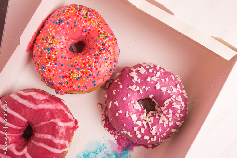 Multi-colored donuts in a white box close-up. Multi-colored donuts in a white box close-up.